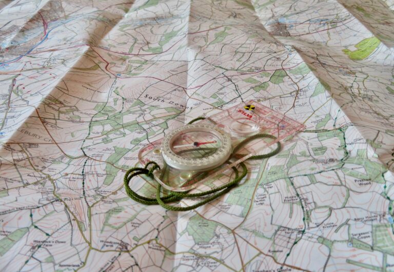 A clear image of a compass and its lanyard lying open on a detailed topographical map, symbolizing precise global navigation, route planning, and real-time cargo tracking.