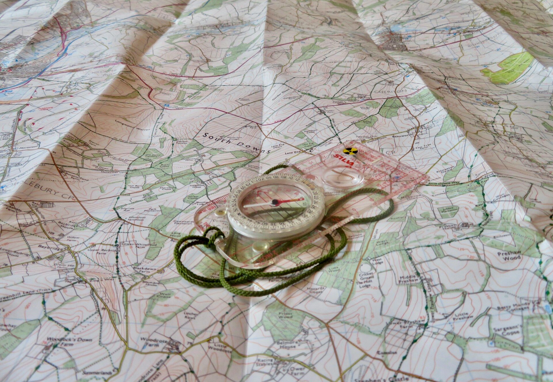 A clear image of a compass and its lanyard lying open on a detailed topographical map, symbolizing precise global navigation, route planning, and real-time cargo tracking.